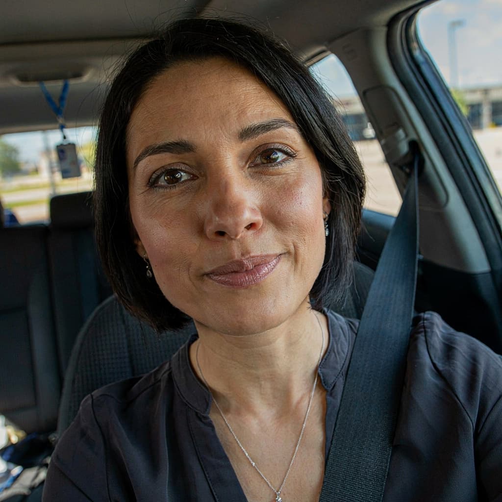 Car selfie of a female sales professional between client visits before headshot generation